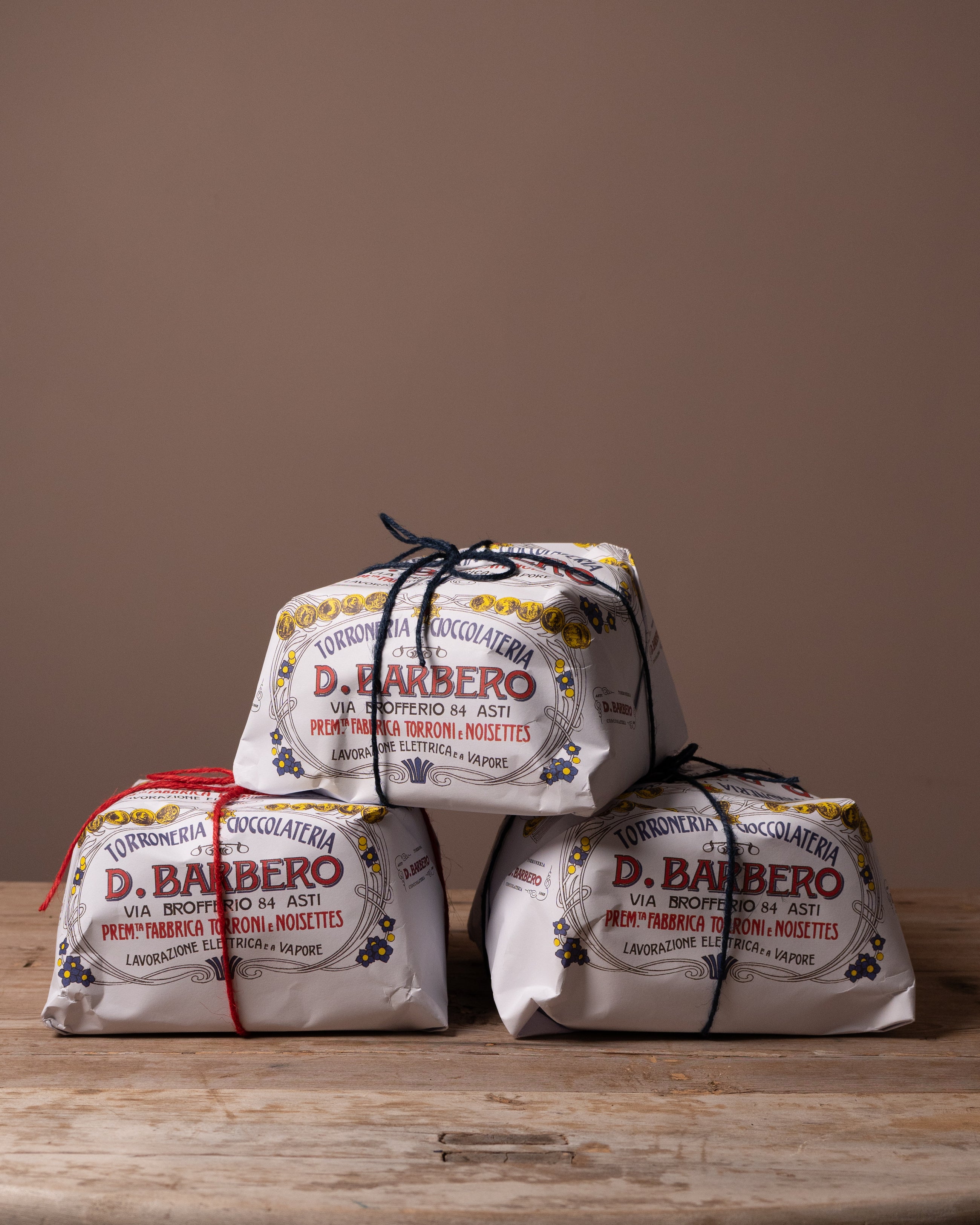 Three packages of D. Barbero Panetonne on a wooden surface with a brown background