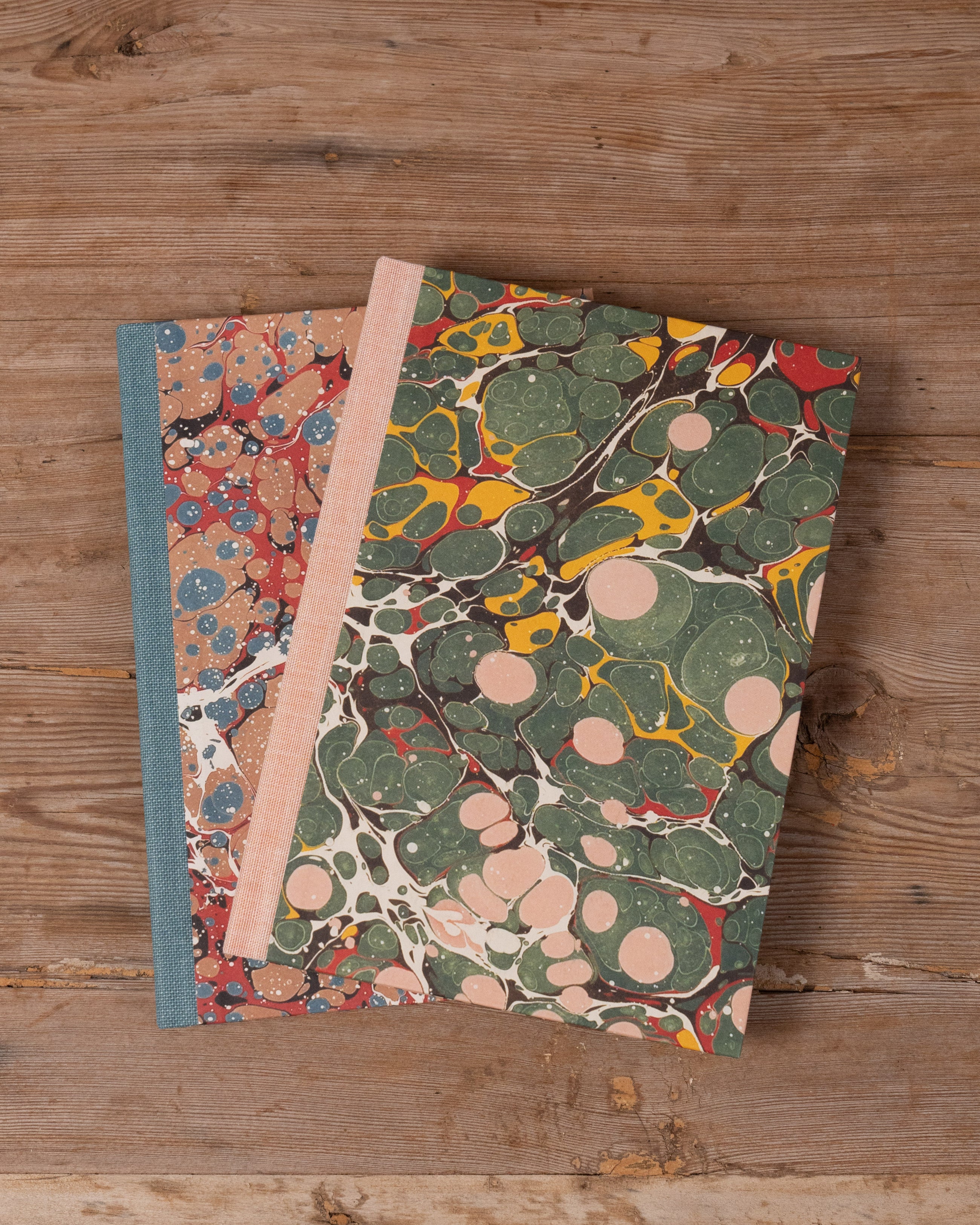 Two notebooks with marbled covers on a wooden surface