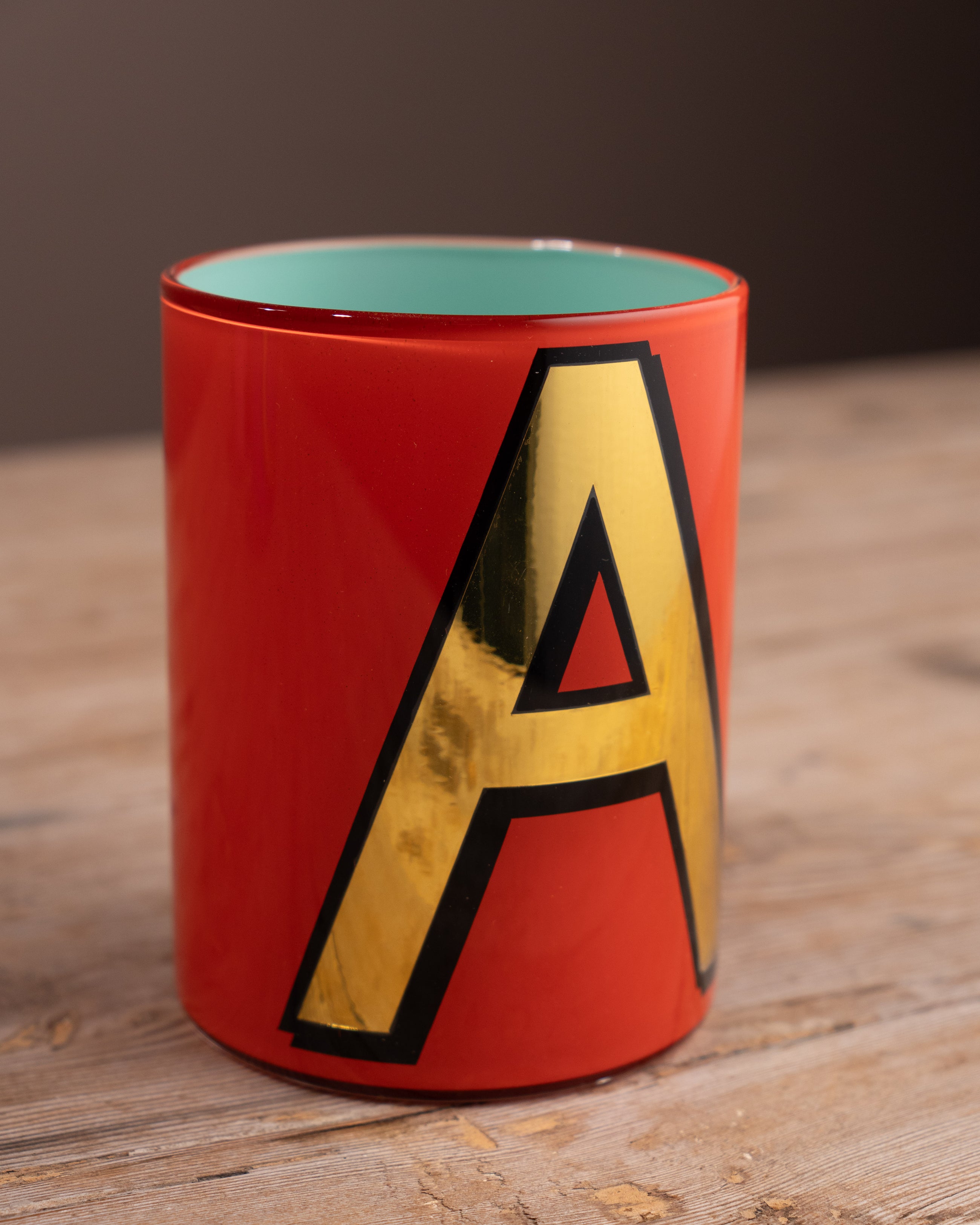 Red mug with a yellow letter 'A' on a wooden surface