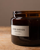 Close up of a scented candle with a label saying "Herb Garden Cook & Butler"