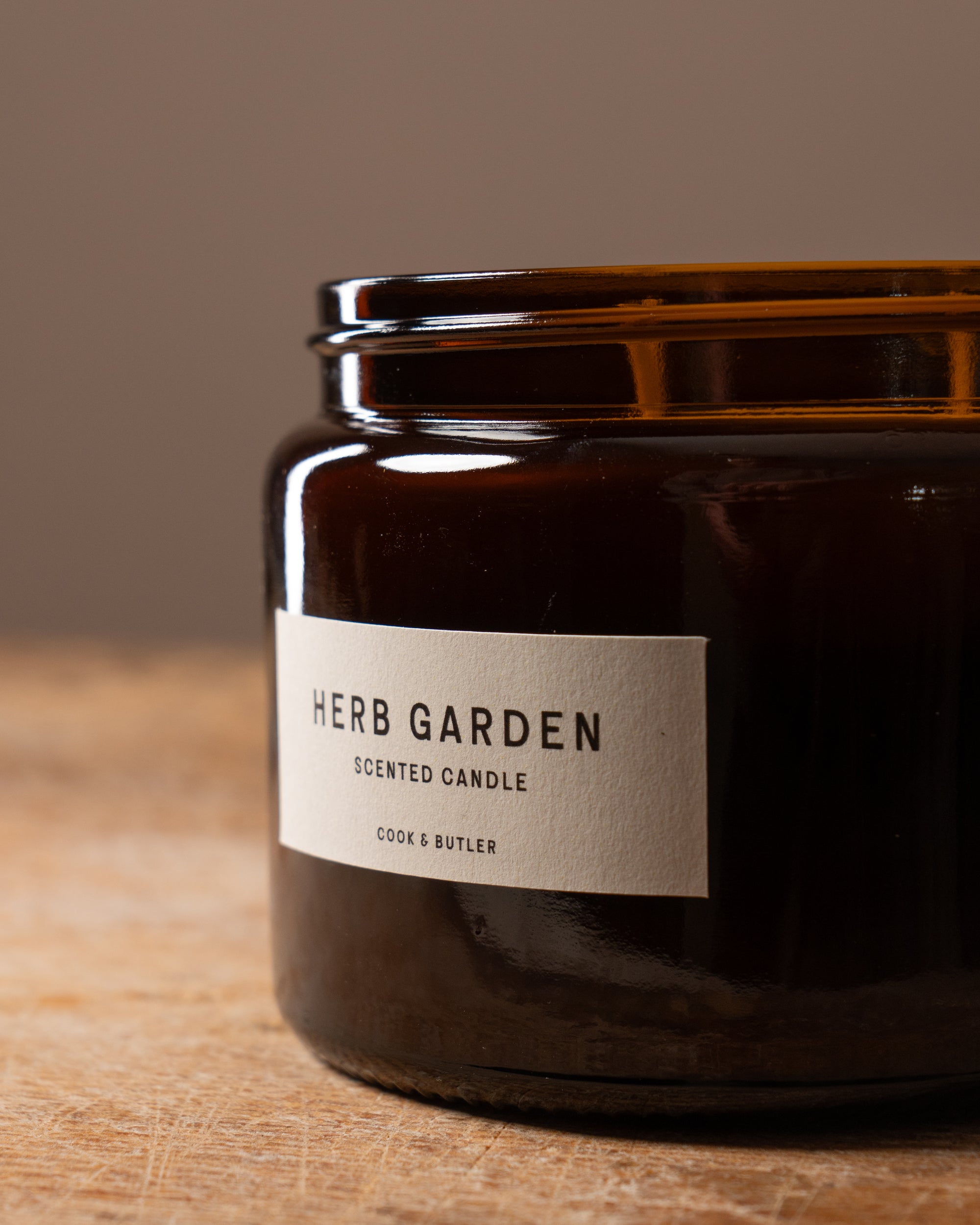 Close up of a scented candle with a label saying "Herb Garden Cook & Butler"