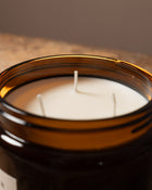 A candle with three wicks with a brown background.