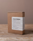 Ampersand Fragrances box on a wooden surface with the text California