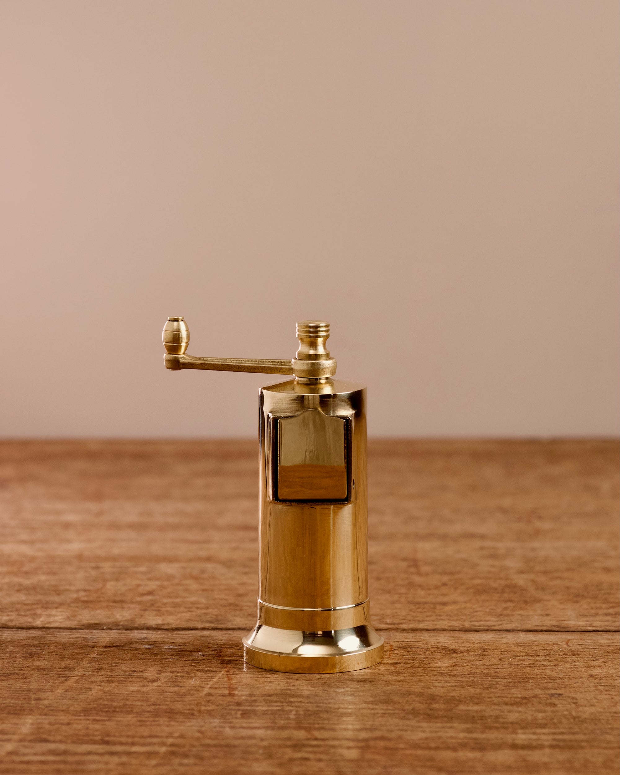 Brass pepper mill with manual grinder on a wooden table