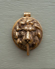 Bronze lion head keyhole cover on a green door