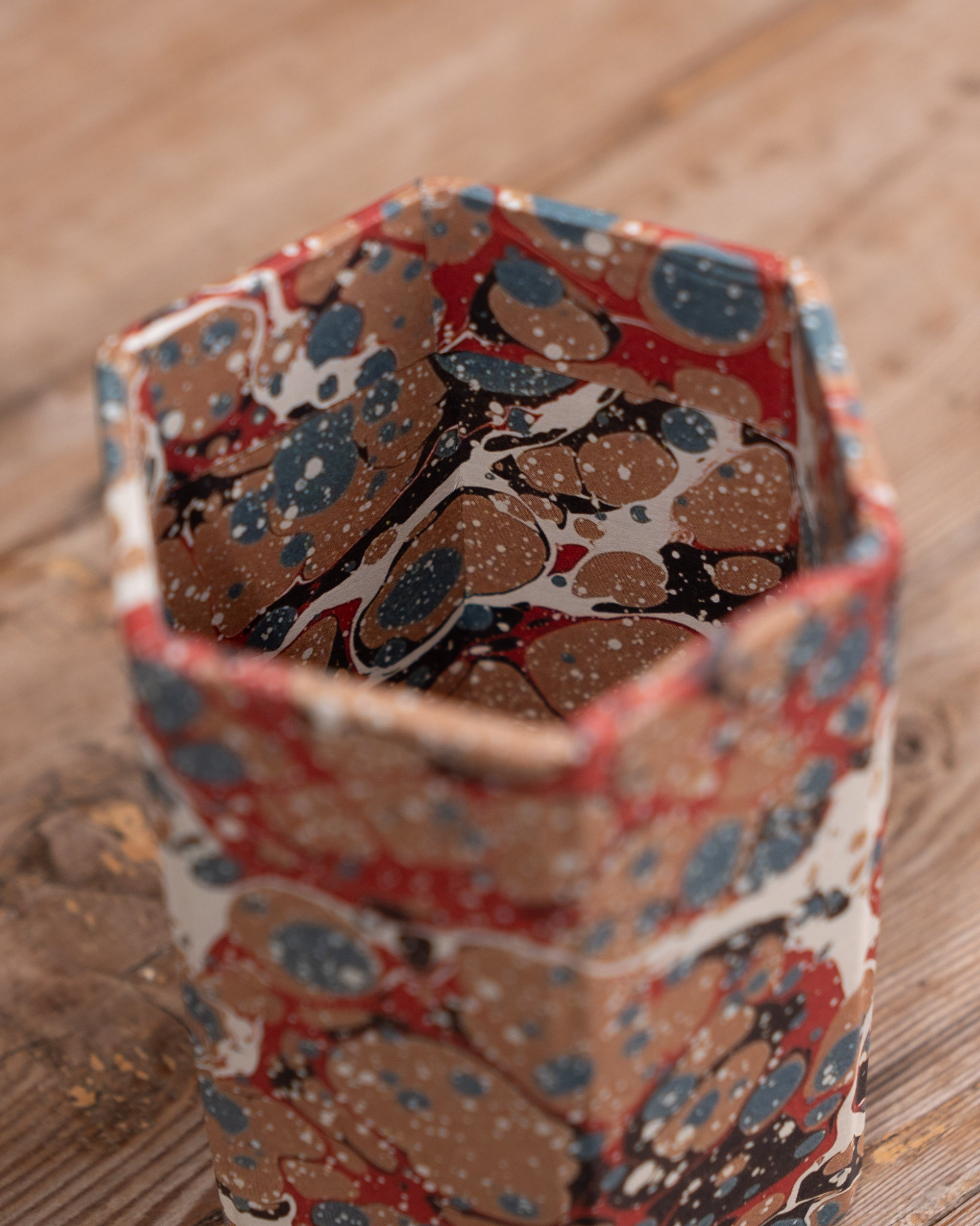 Hexagonal container with floral pattern on a wooden surface