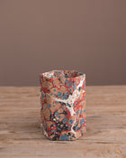 Marbled hexagonal pen pot on a wooden surface with a brown background