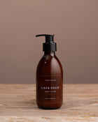Brown bottle with black pump on a wooden surface and brown background