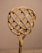 Woven rattan heart-shaped object on a wooden surface with a brown background