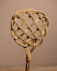 Woven rattan heart-shaped object on a wooden surface with a brown background