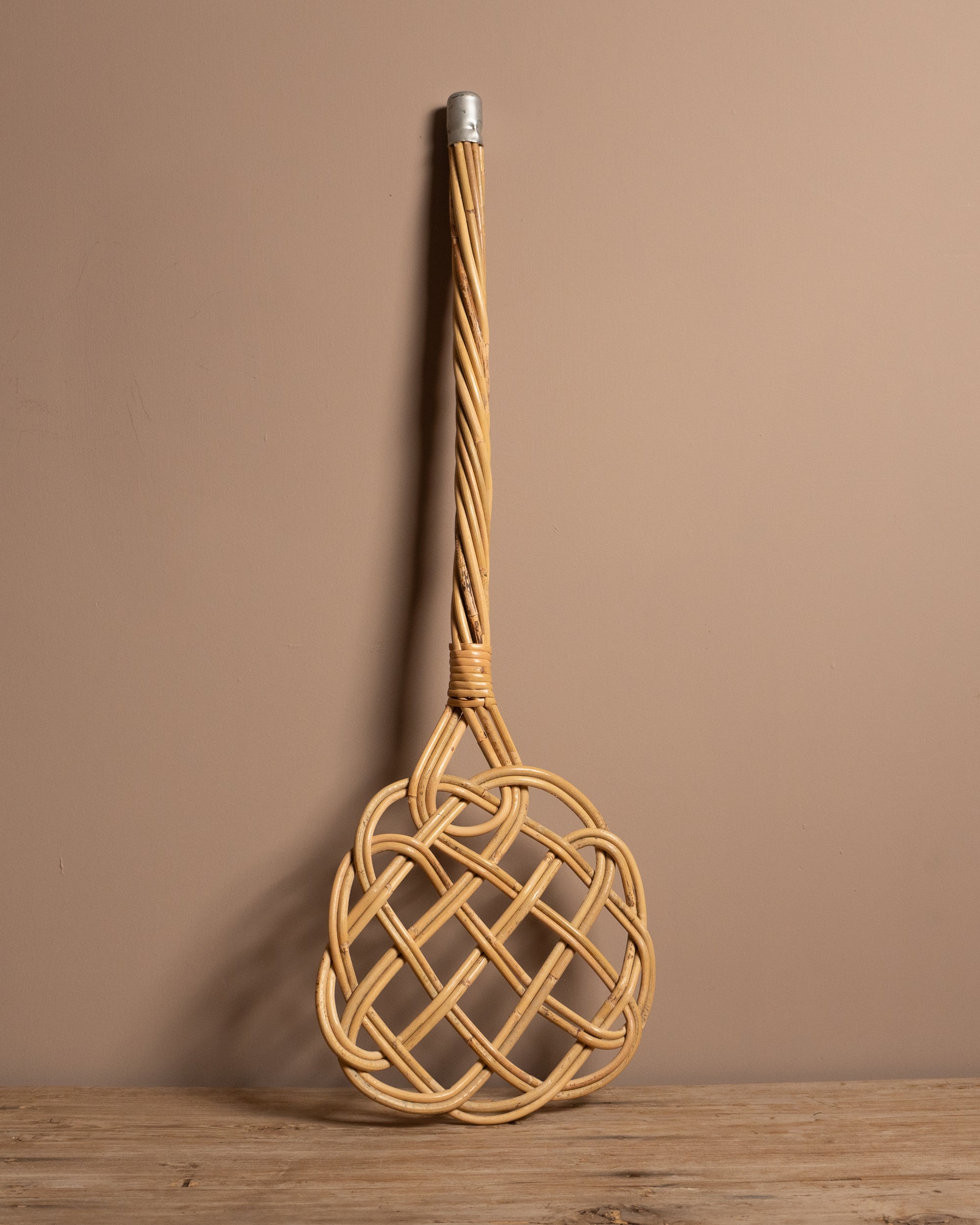 Carpet beater on a wooden surface and brown background