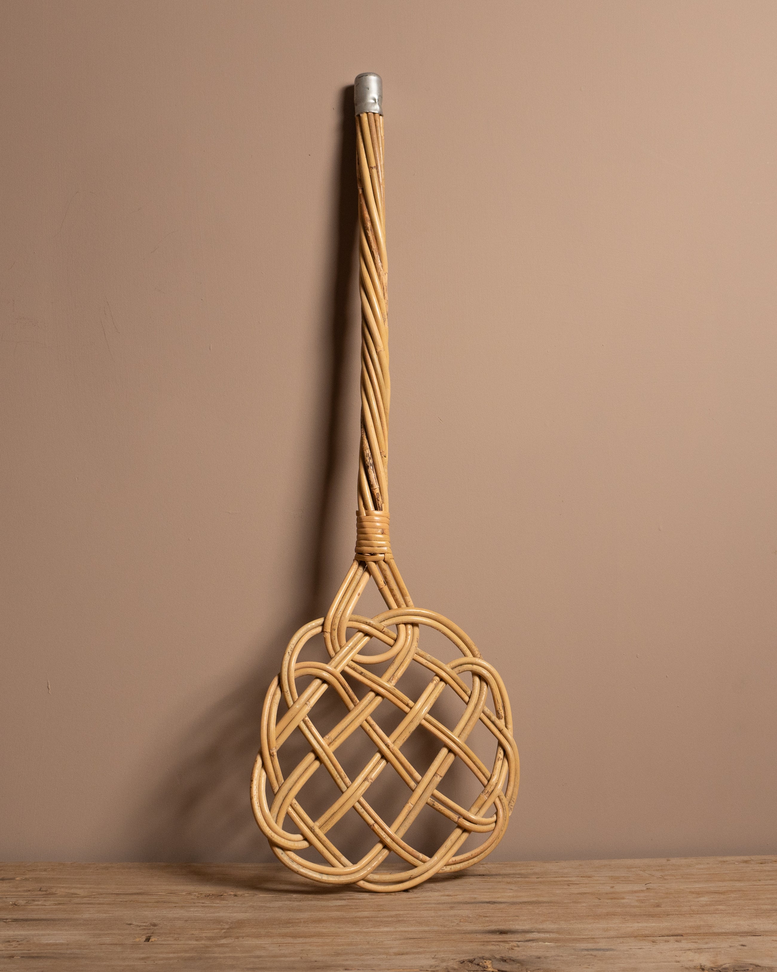 Carpet beater on a wooden surface and brown background