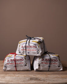 Three packages of D. Barbero Panetonne on a wooden surface with a brown background