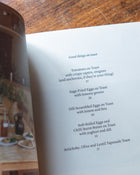 Cookbook titled 'Midweek Recipes' by Jess Elliott Dennison opened on a wooden able
