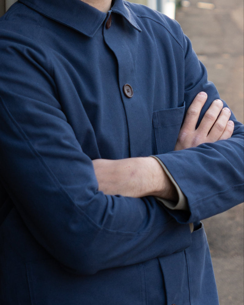 Person wearing a blue coat with arms crossed, blurred background