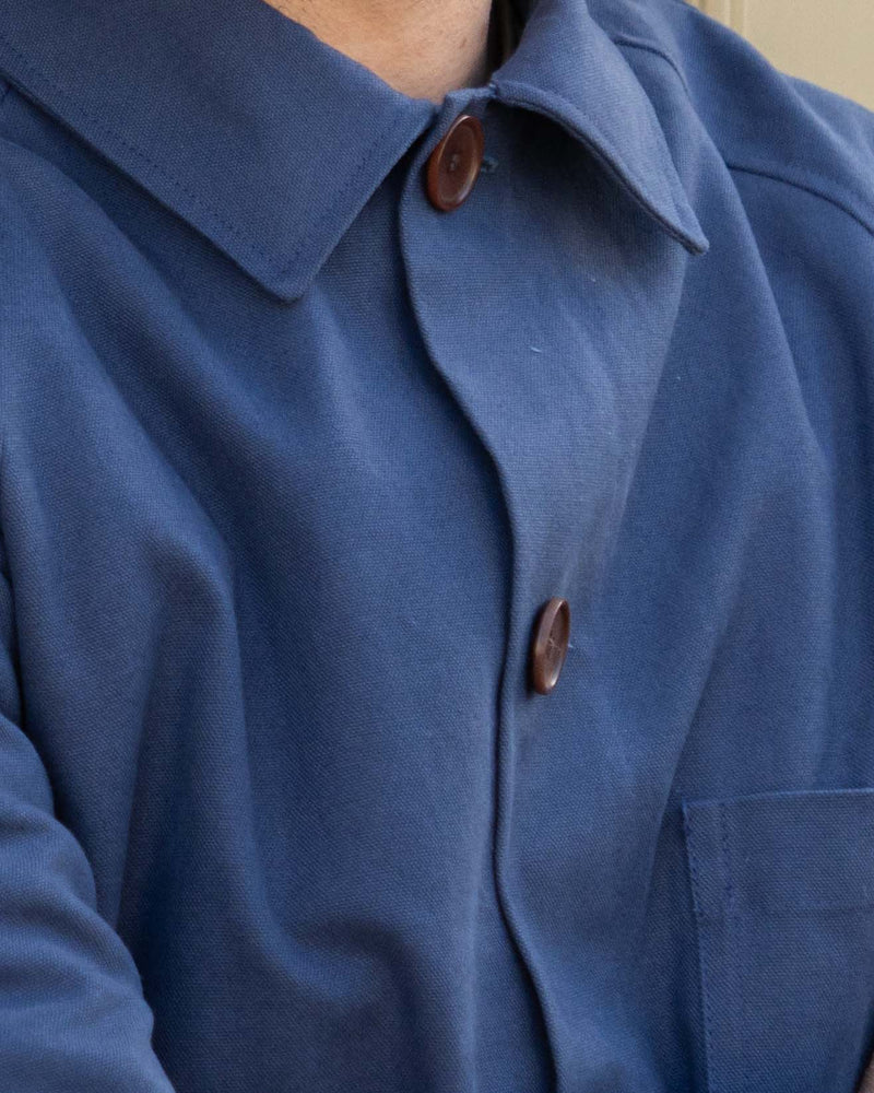 Close-up of a blue coat with brown buttons on a neutral background