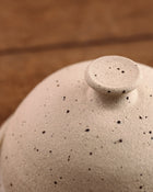 Close-up of a speckled ceramic butter dish with a lid on a wooden surface
