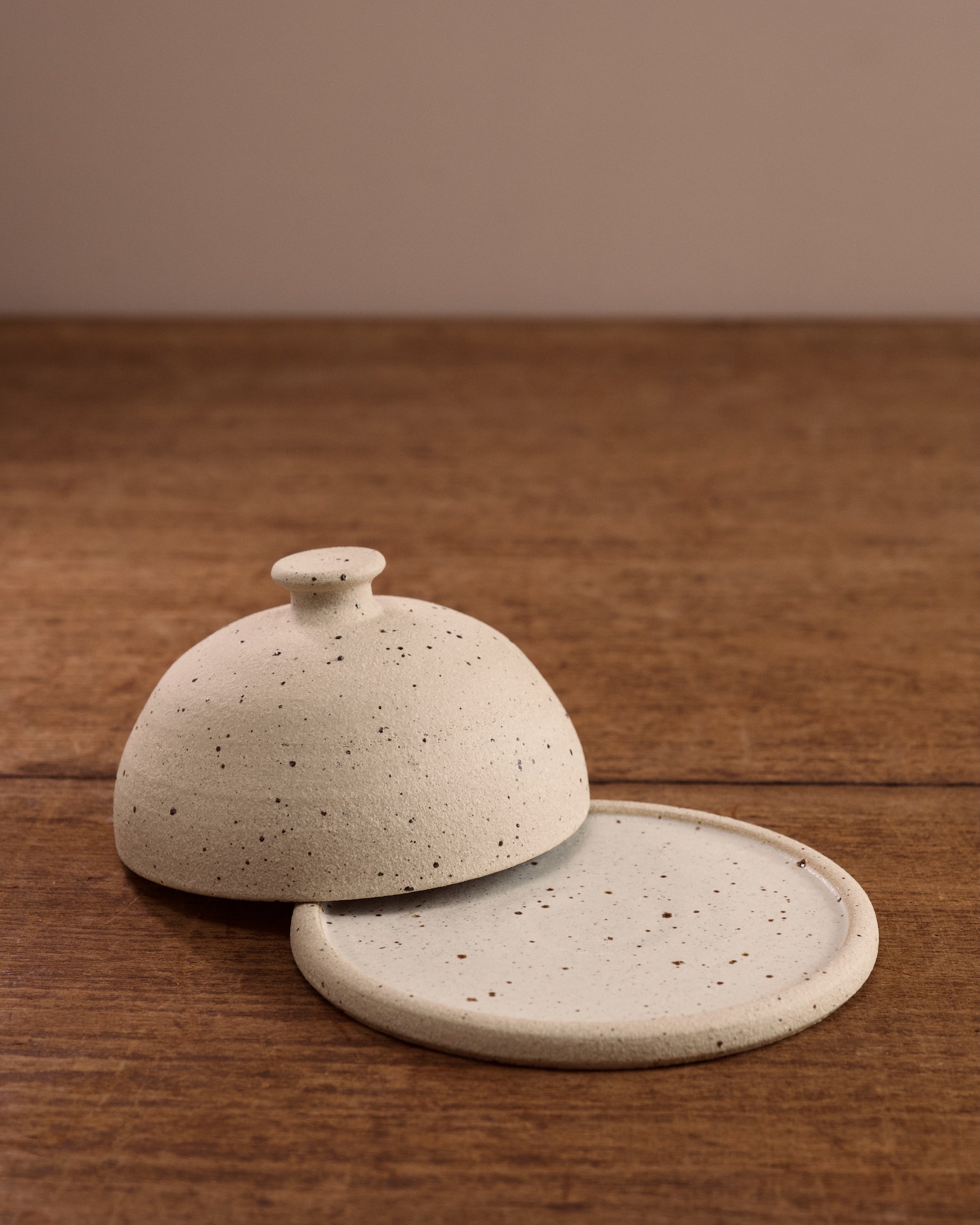 Speckled ceramic cloche butter dish on a wooden surface