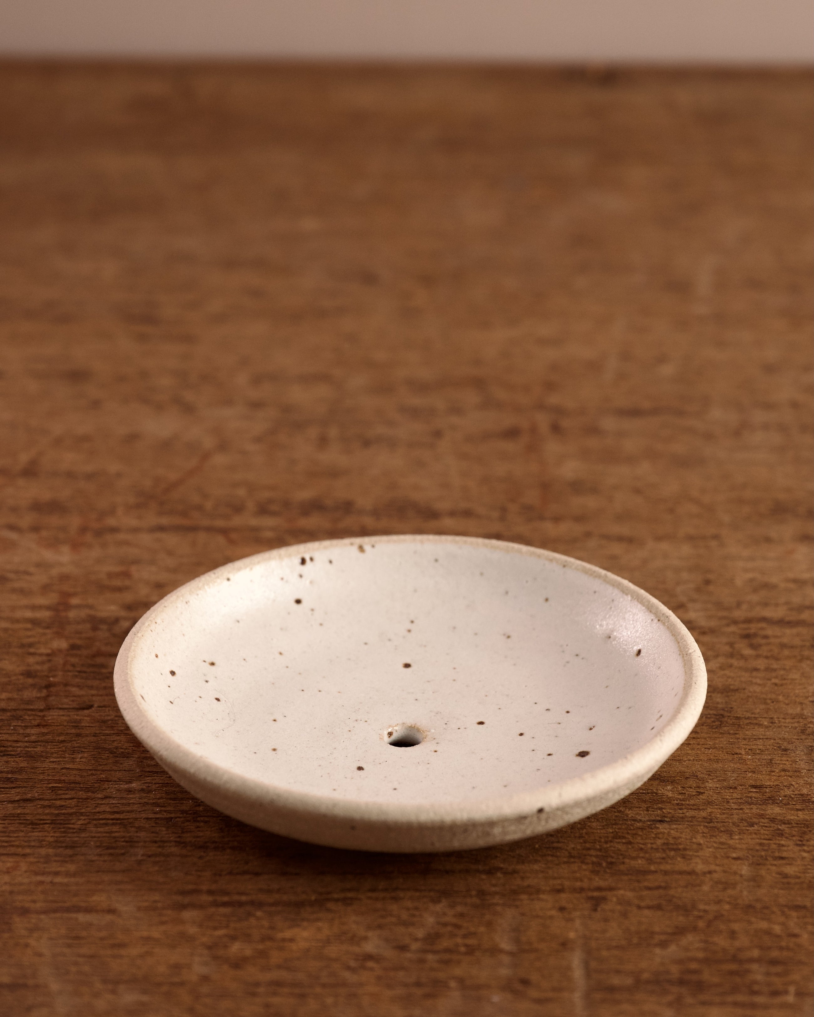 Speckled ceramic soap dish on a wooden surface