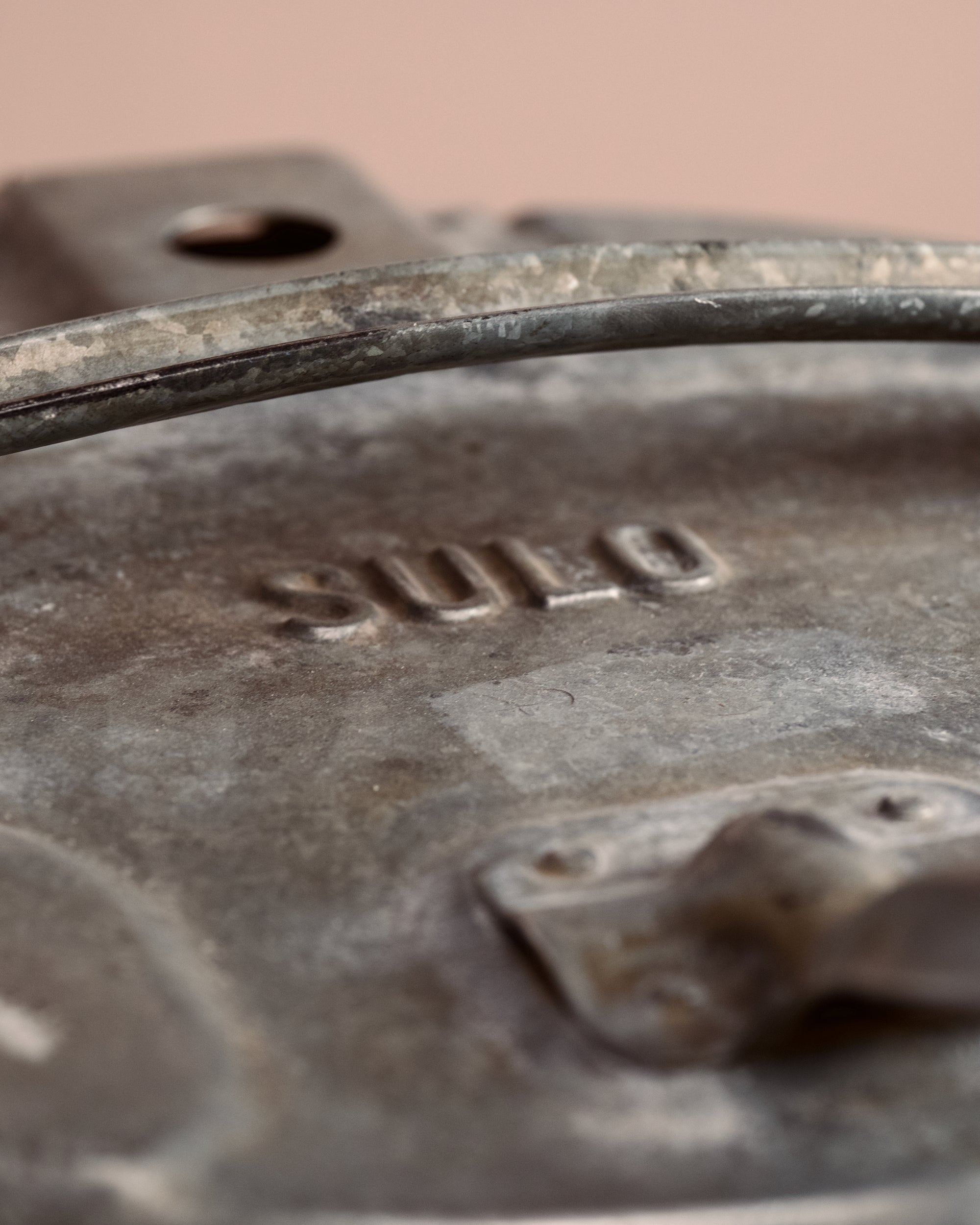 Vintage-style metal ash can on a wooden surface with a beige background