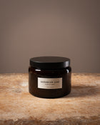 Cook and Butler scented candle on a wooden worktop with a label saying "geranium leaf"