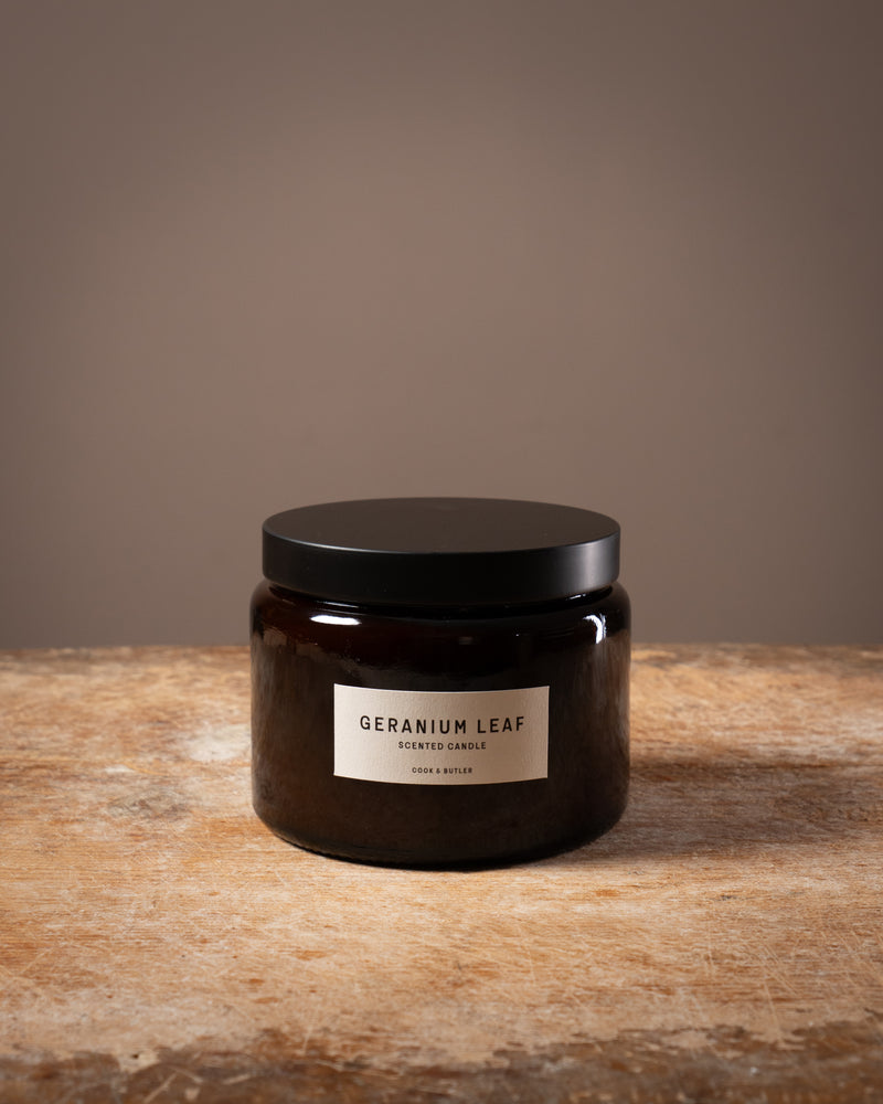 Cook and Butler scented candle on a wooden worktop with a label saying "geranium leaf"