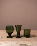 Three Recycled green drinking glasses on a wooden table