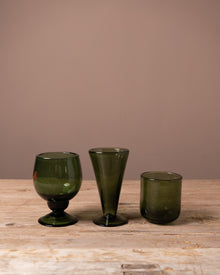 Three Recycled green drinking glasses on a wooden table
