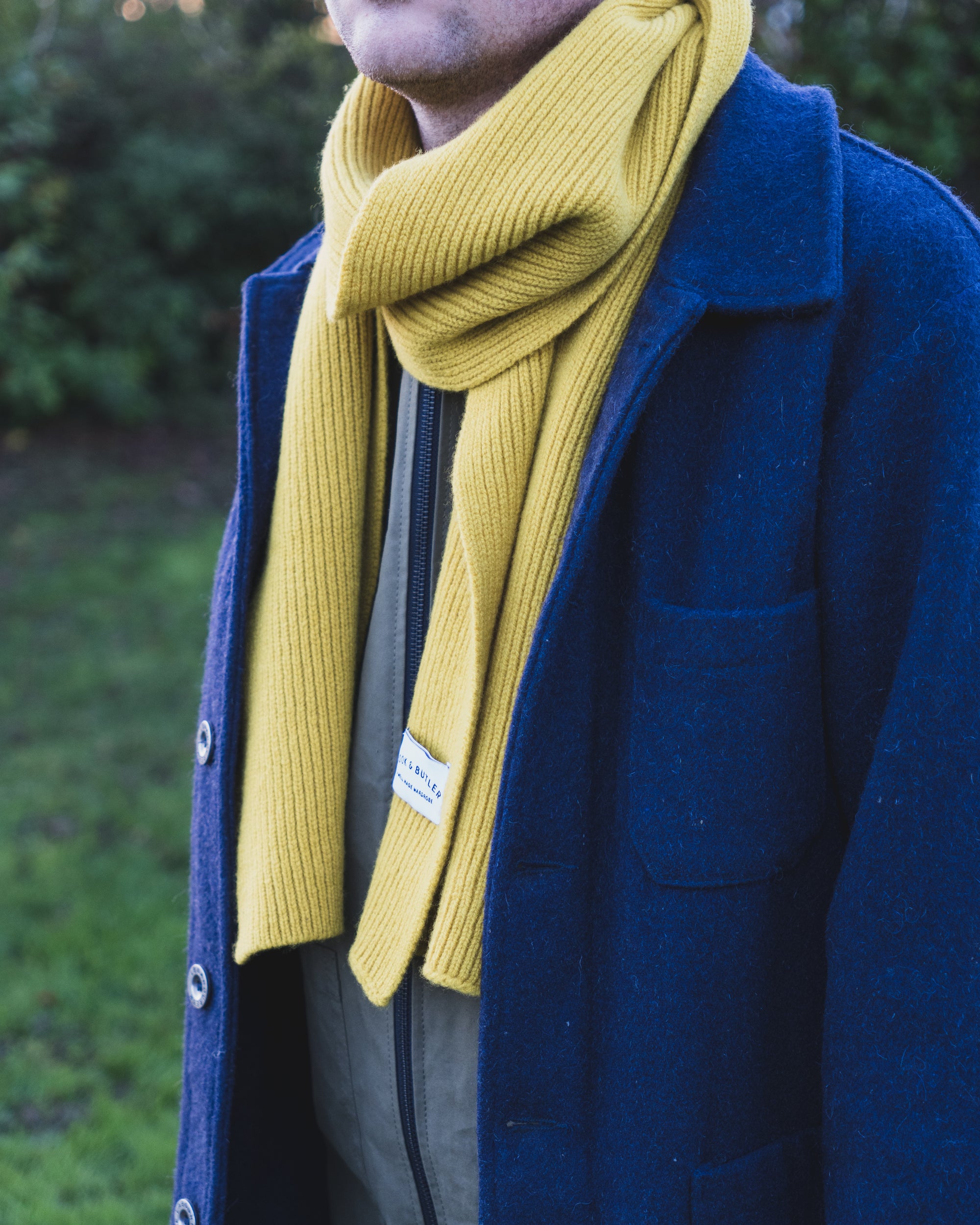 Person wearing a blue coat and yellow scarf outdoors