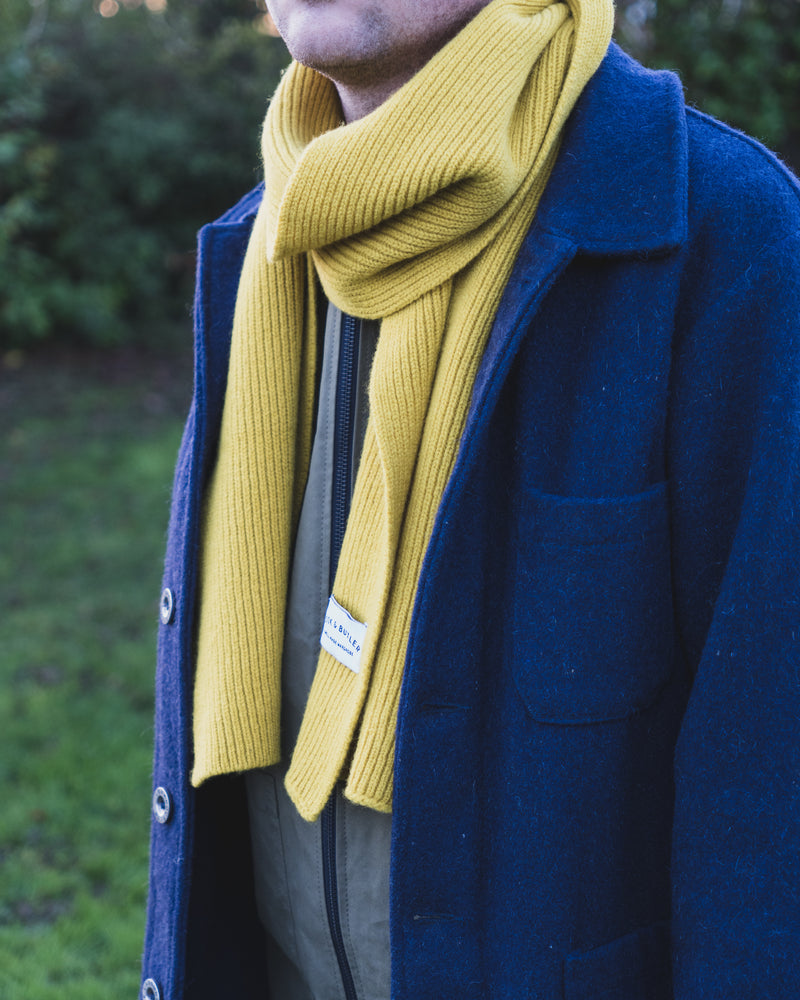 Person wearing a blue coat and yellow scarf outdoors