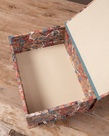 Decorative storage box with a colourful marbled paper pattern on a wooden surface