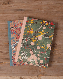 Two notebooks with marbled covers on a wooden surface