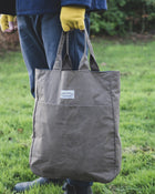 Person with yellow gloves holding a 'Cook and Butler' tote bag.