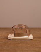 Wire cage mouse trap on a wooden base against a brown background