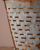 Rusticated metal basket with perforated design on a neutral background