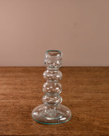 Clear glass candlestick on a wooden surface with a beige background