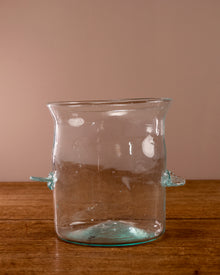 Clear glass vase with unique design on a wooden surface and brown background