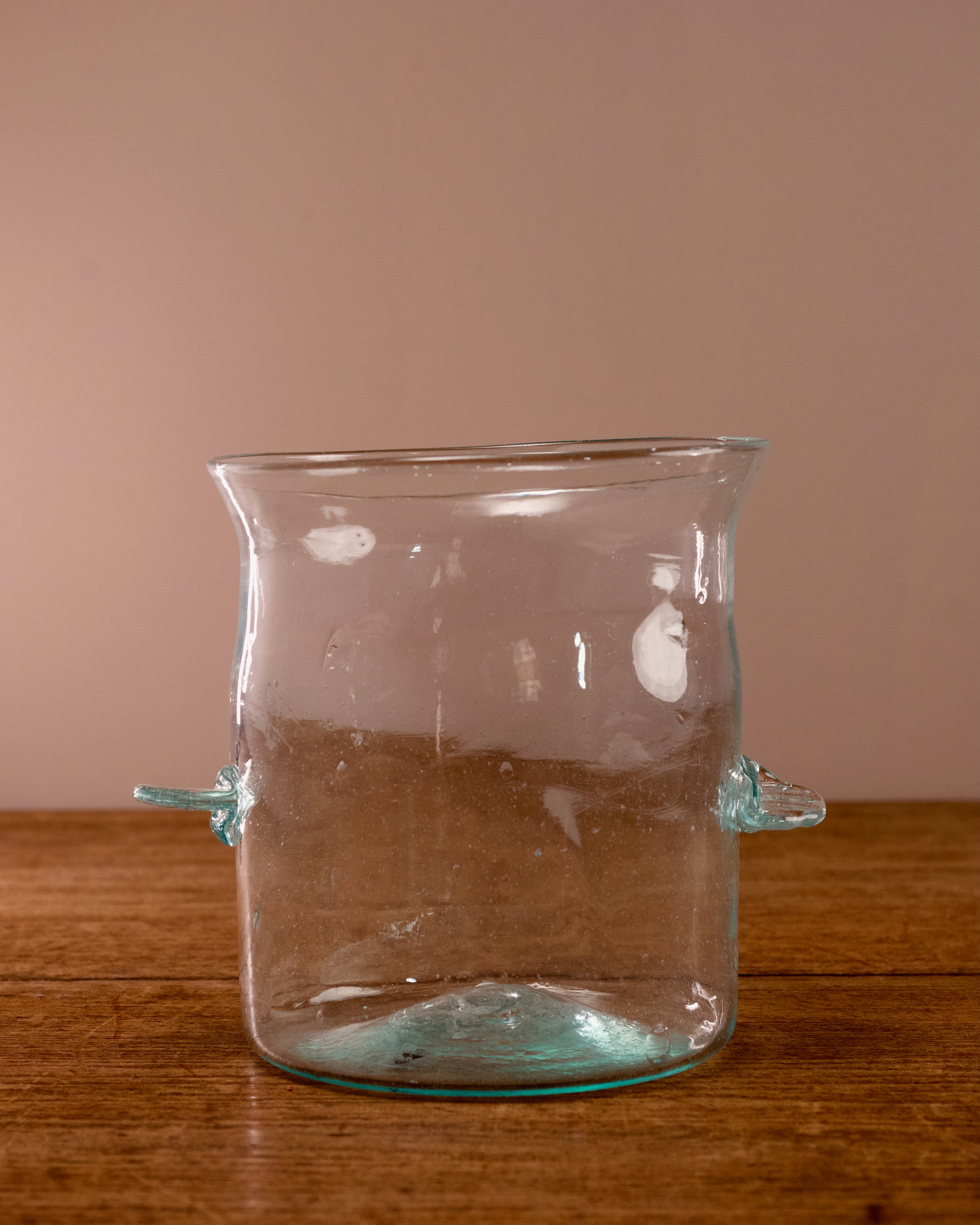 Clear glass vase with unique design on a wooden surface and brown background