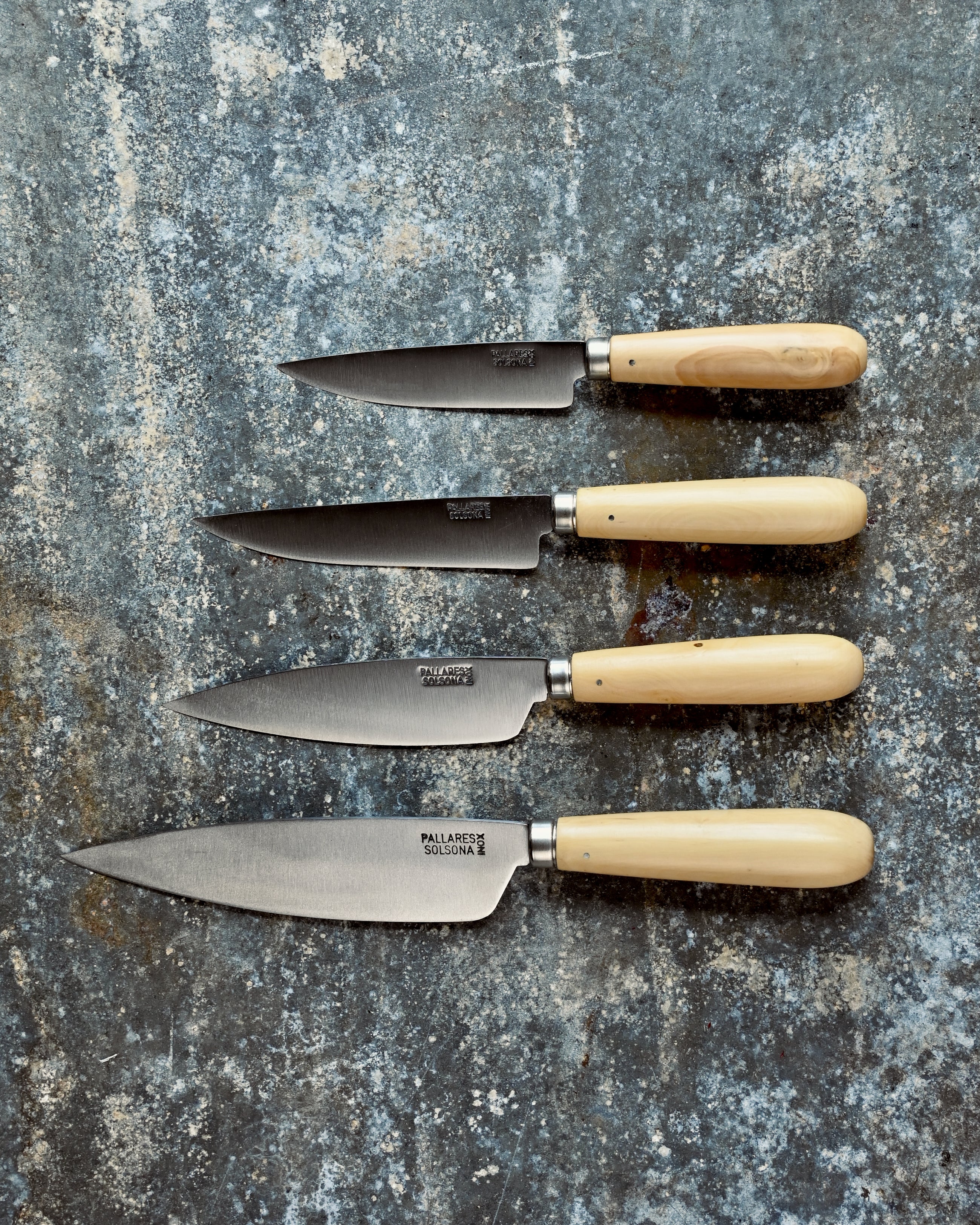 Four knives with beige handles on a textured stone surface