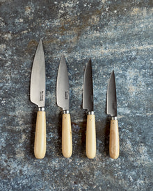Set of four knives with wooden handles on a textured stone surface