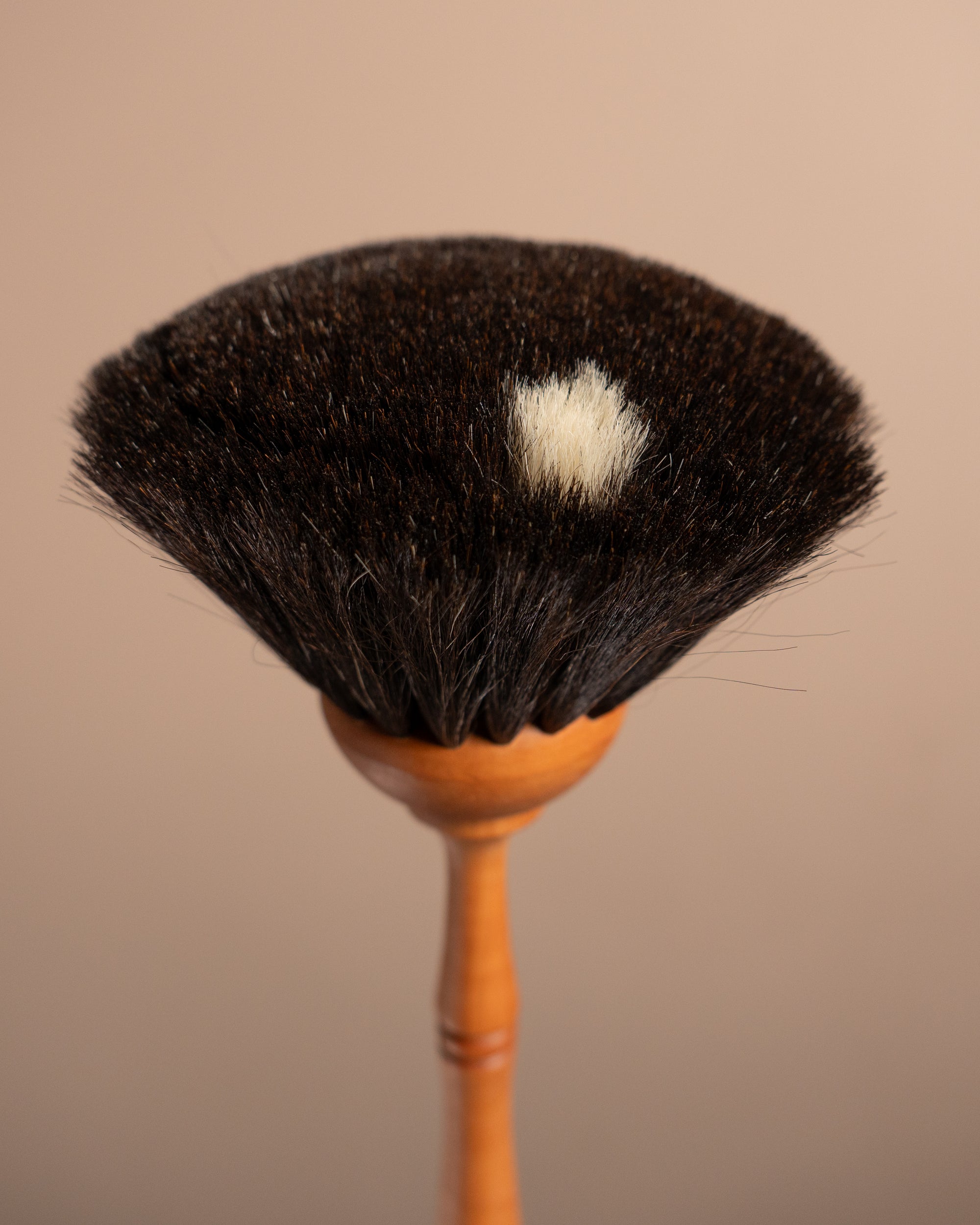 Brush with black bristle head and wooden handle on a beige background