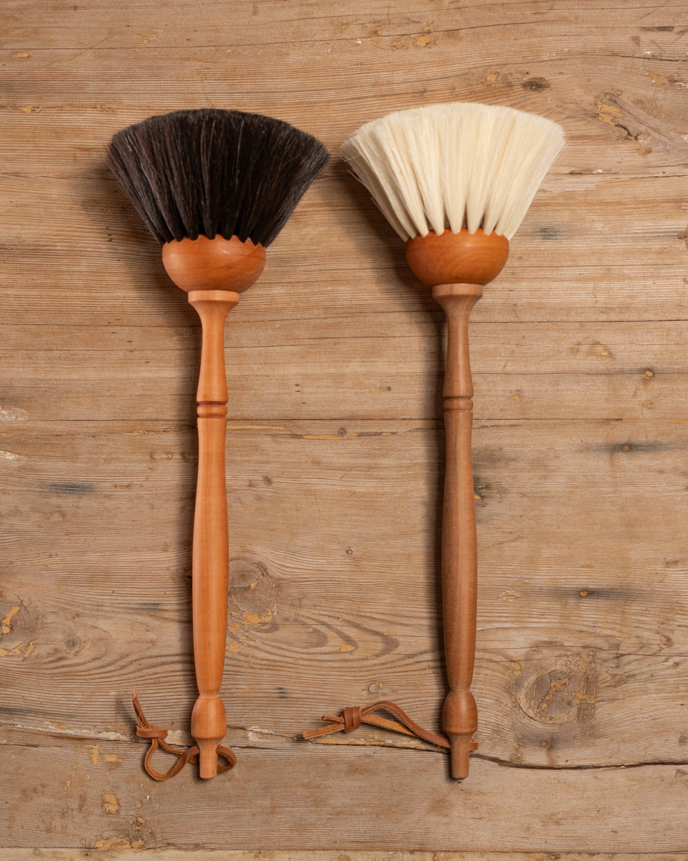 Two wooden brushes with bristle heads on a wooden background