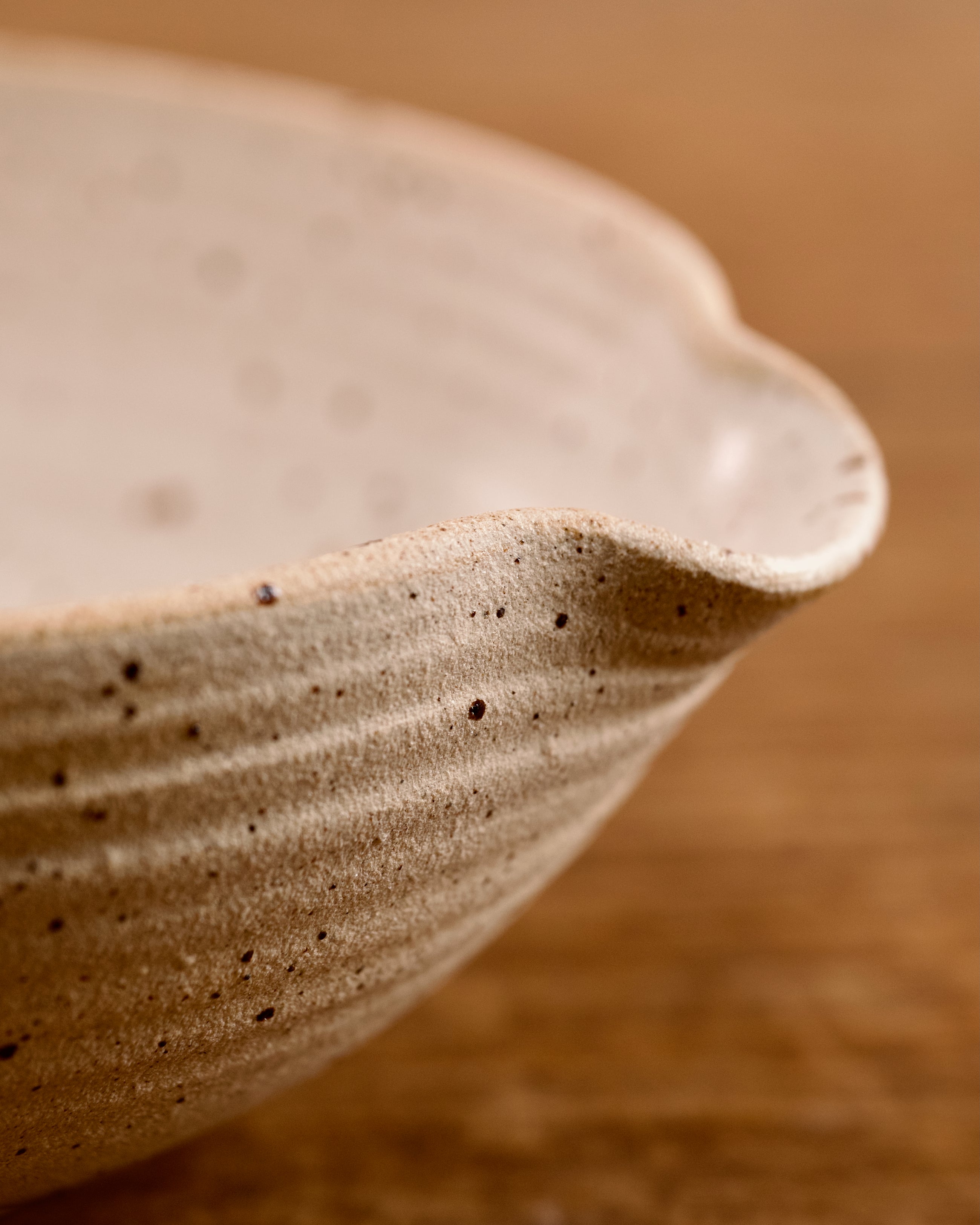 Speckled ceramic mixing bowl on a wooden surface with a beige background