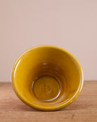 Terracotta bowl with yellow glazed interior  on a wooden surface.