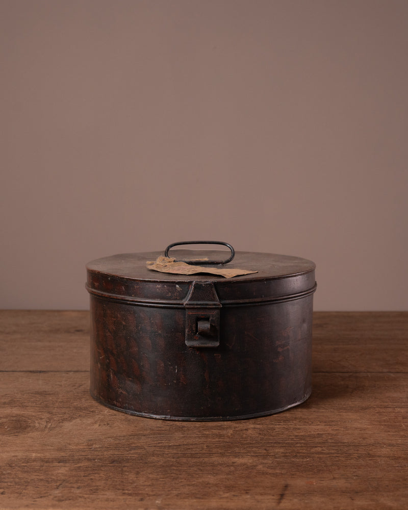 Vintage-style metal storage box with a lid on a wooden surface against a brown background