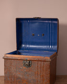 Rustic metal trunk with a blue lid on a beige background