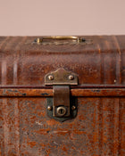 Close-up of an old, rusty suitcase with a lock on a beige background