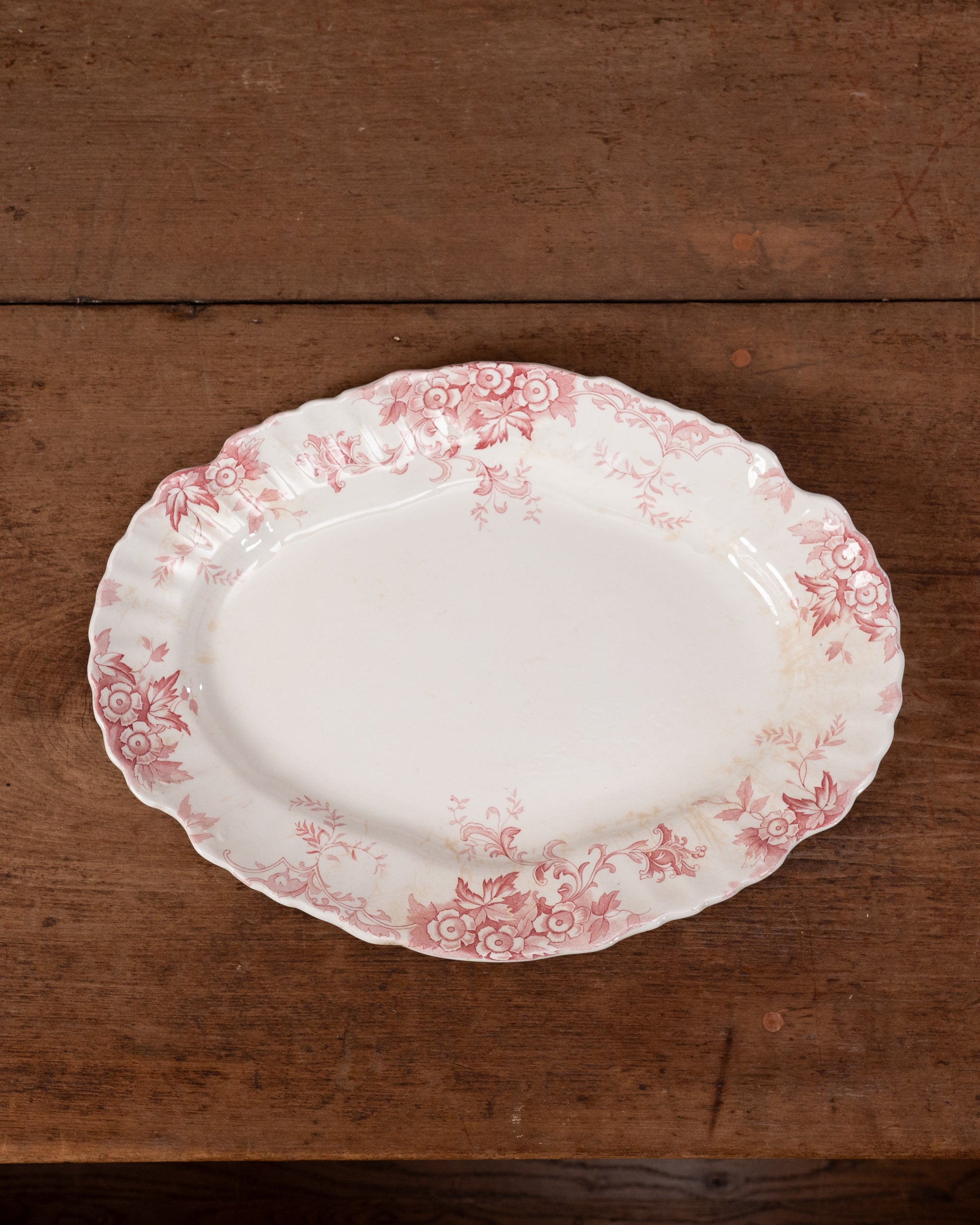 Decorative plate with pink floral pattern on a wooden surface