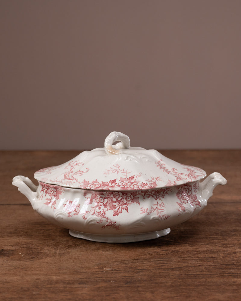 White ceramic tureen with red floral pattern on a wooden surface