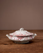 White ceramic tureen with red floral pattern on a wooden surface